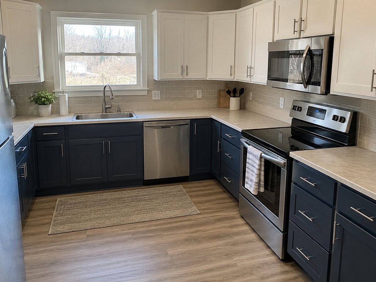 Remodeled kitchen with navy base cabinets, white upper cabinets, stainless appliances and a tile backsplash